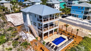 A multi-story building with a rooftop pool, surrounded by other residential structures. - The Sand Pearl-New/N Cape/Steps to Beach/5 BR (Port St. Joe)