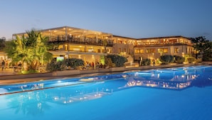 A hotel with a large outdoor swimming pool, multiple balconies, and well-lit outdoor areas. - VOI Tanka Selected (Villasimius)