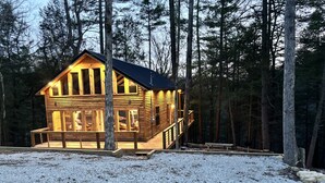 A wooden cabin with a deck, surrounded by trees. - Unwind at Whispering Woods / Hot Tub, Waterfall, Arcade & Nature (camton)