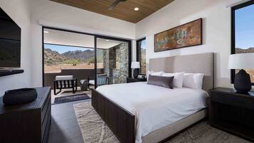 Un dormitorio con una cama grande, ventilador de techo, pared de piedra y vistas al desierto.