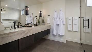 A modern bathroom with a large mirror, a marble countertop, and multiple white towels.
