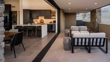 Una cocina moderna con armarios oscuros, una isla de mármol y una pared decorativa de piedra.