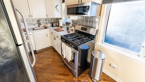 Une cuisine moderne avec des armoires blanches, des appareils en acier inoxydable et un plancher en bois.
