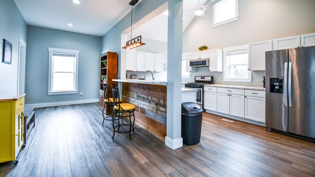 Una cocina moderna con armarios blancos, un refrigerador de acero inoxidable y una isla de madera con taburetes de bar.
