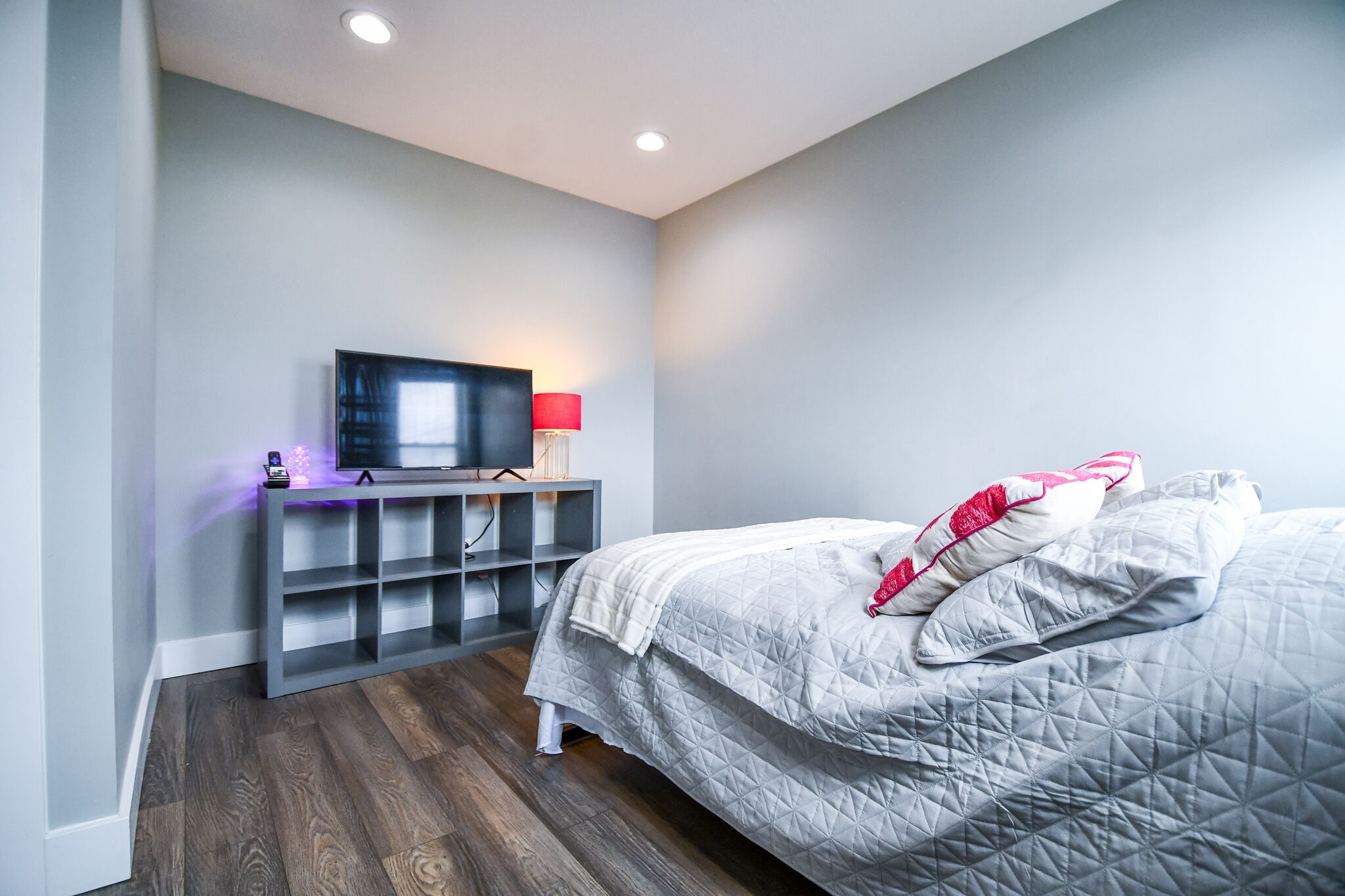 Une chambre à coucher avec un lit, un téléviseur posé sur un meuble et une étagère.