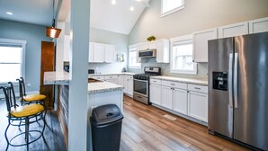 Una cocina moderna con armarios blancos, electrodomésticos de acero inoxidable y suelo de madera.