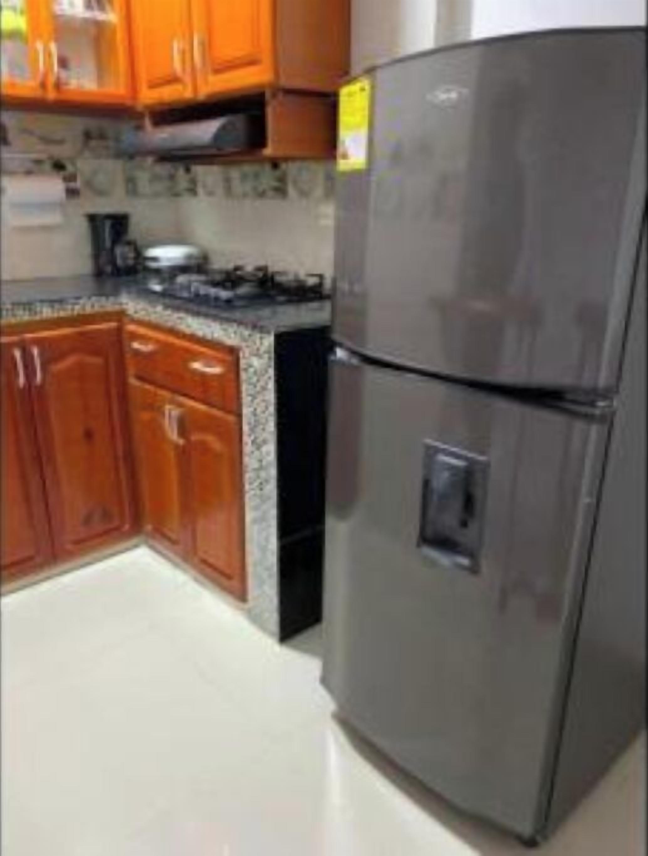A kitchen with wooden cabinets, a stainless steel refrigerator, and a granite countertop.
