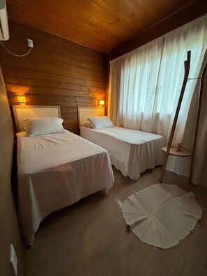Une chambre avec deux lits, des murs en bois et une petite table avec une lampe.