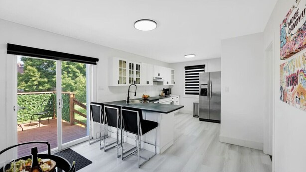 A modern kitchen with a central island, white cabinetry, and a stainless steel refrigerator.