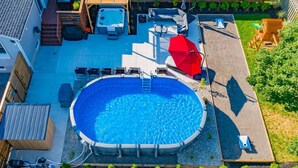 A backyard with a hot tub, a covered seating area, and a swimming pool.