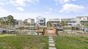 A marina with docked boats, a wooden pier, and waterfront houses. - Beach House - Private Dock + Walk to the Beach (Holden Beach)
