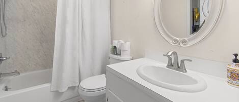 A bathroom with a bathtub, toilet, and sink.