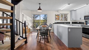 Una cucina moderna con isola centrale, pavimento in legno e vista all'esterno.