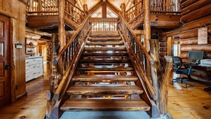 A wooden staircase with a metal railing leading to a loft area.
