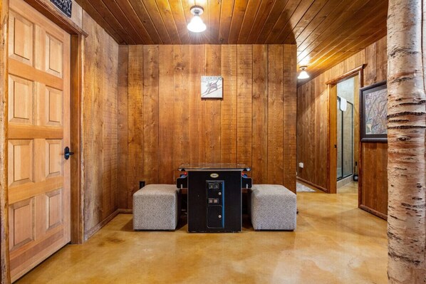 A wooden-paneled room with a black heater, two cushioned benches, and a door on the left.