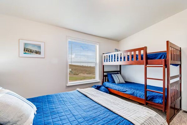 Een slaapkamer met stapelbedden, een raam met zonwering en een lijst met foto aan de muur.