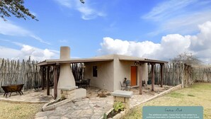 Un bâtiment d’un seul étage doté d’une terrasse en pierre, d’un espace extérieur couvert aménagé en coin salon et d’un jardin de cactus.