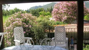 Un espacio de estar al aire libre cubierto con una mesa y sillas, con vistas a un jardín de árboles florecientes en tonos rosados y montañas al fondo.