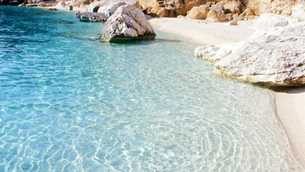 Una playa despejada con aguas poco profundas y rocas.