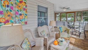 A covered porch with wicker furniture, a table, and chairs.