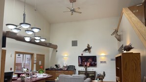 A spacious living area with a fireplace, a television, and a dining area with a wooden table and chairs. - AuSable Valley Inn (Mio)