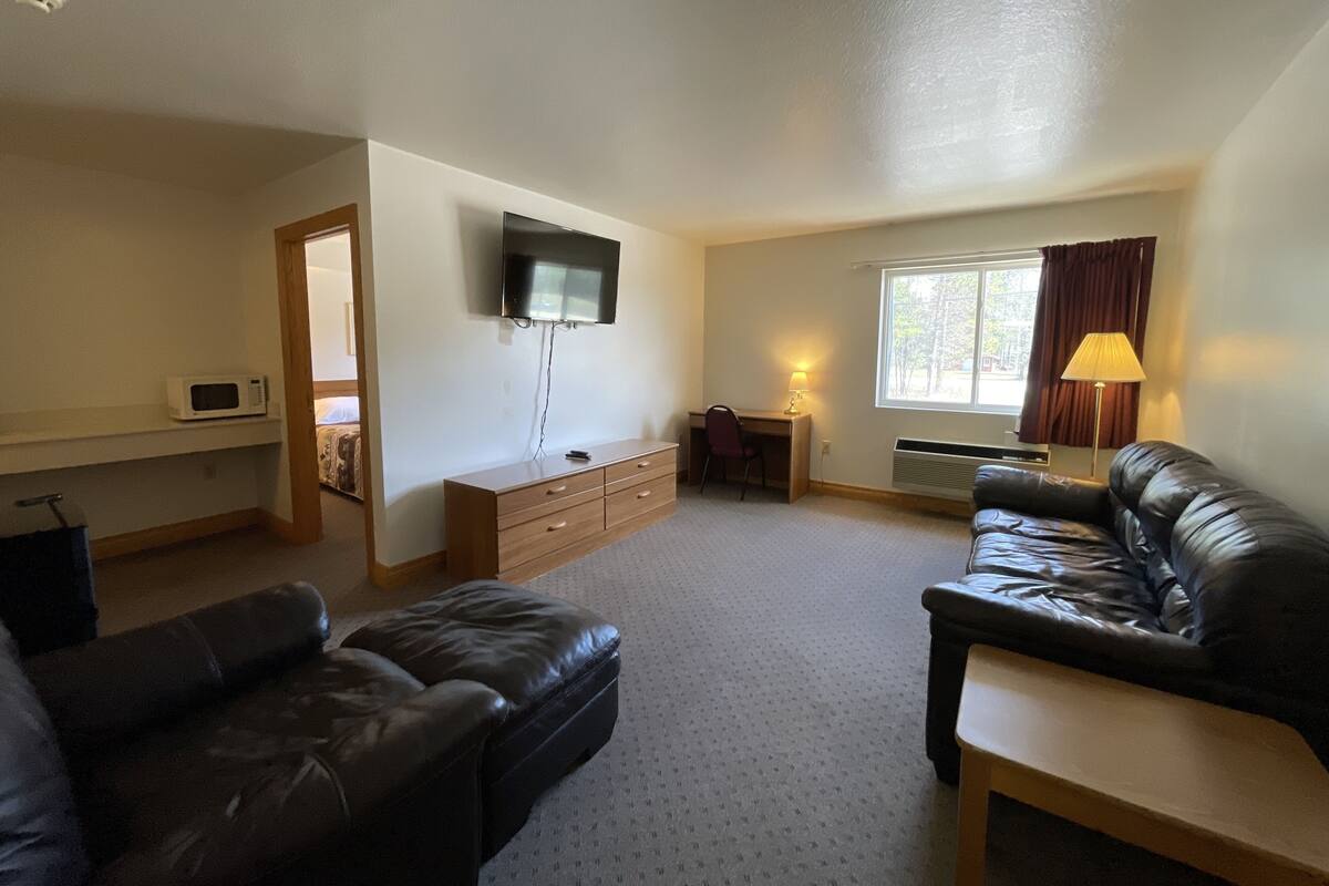 A living room with a flat-screen TV, a desk with a chair, a sofa, and a lamp.