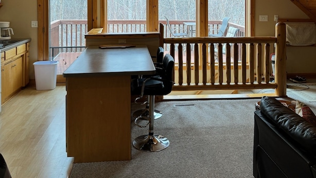 A cozy attic bedroom with a sloped wooden ceiling, a desk, and a chair. There are three large windows offering a view of a snowy deck. - Welcome to Leech Lake Lodge! (Federal Dam)