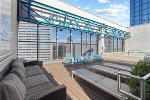 A rooftop deck with outdoor seating, a pool, and a view of the cityscape.