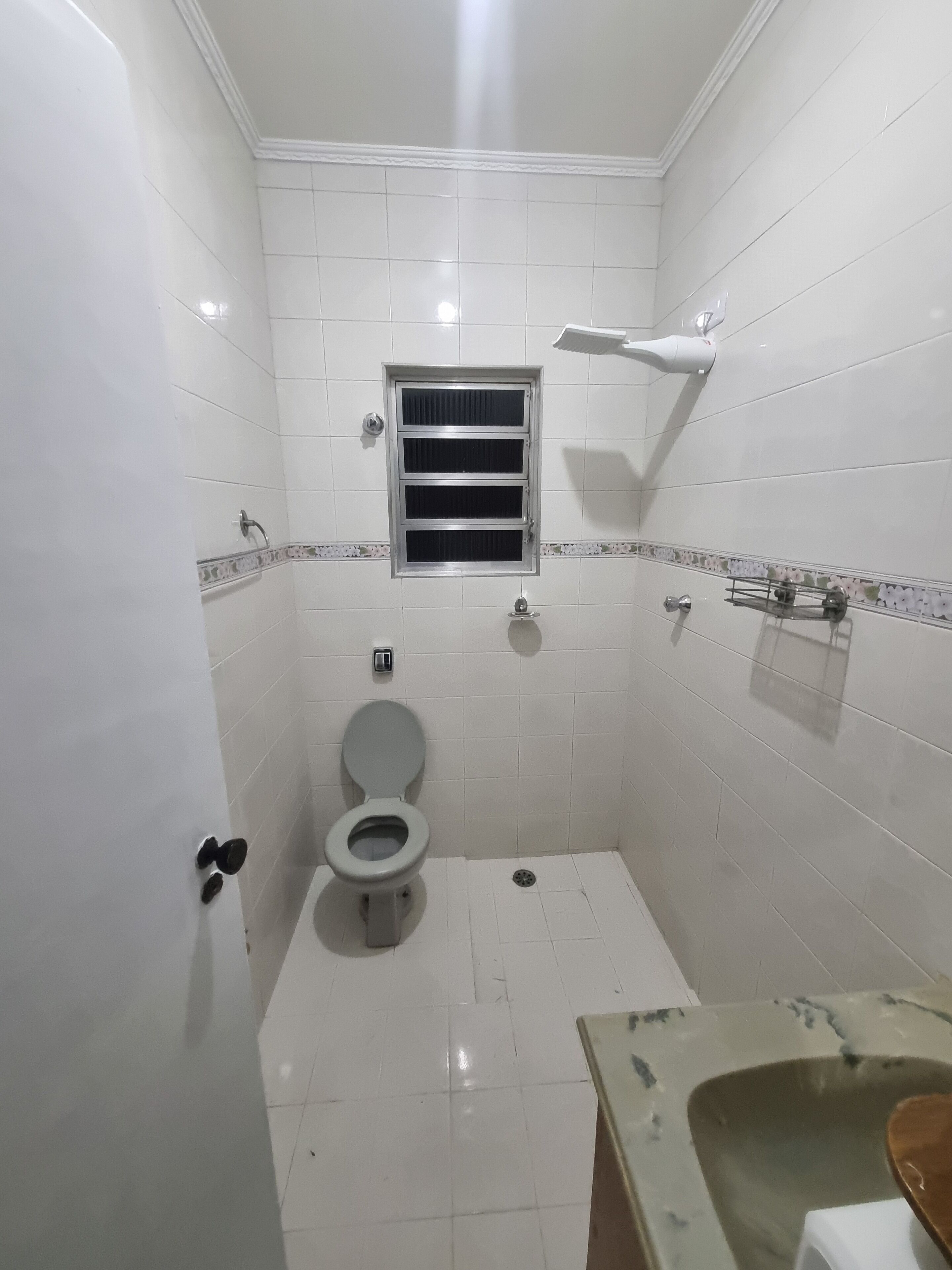 Un baño pequeño con azulejos, un inodoro, una ventana y una ducha.