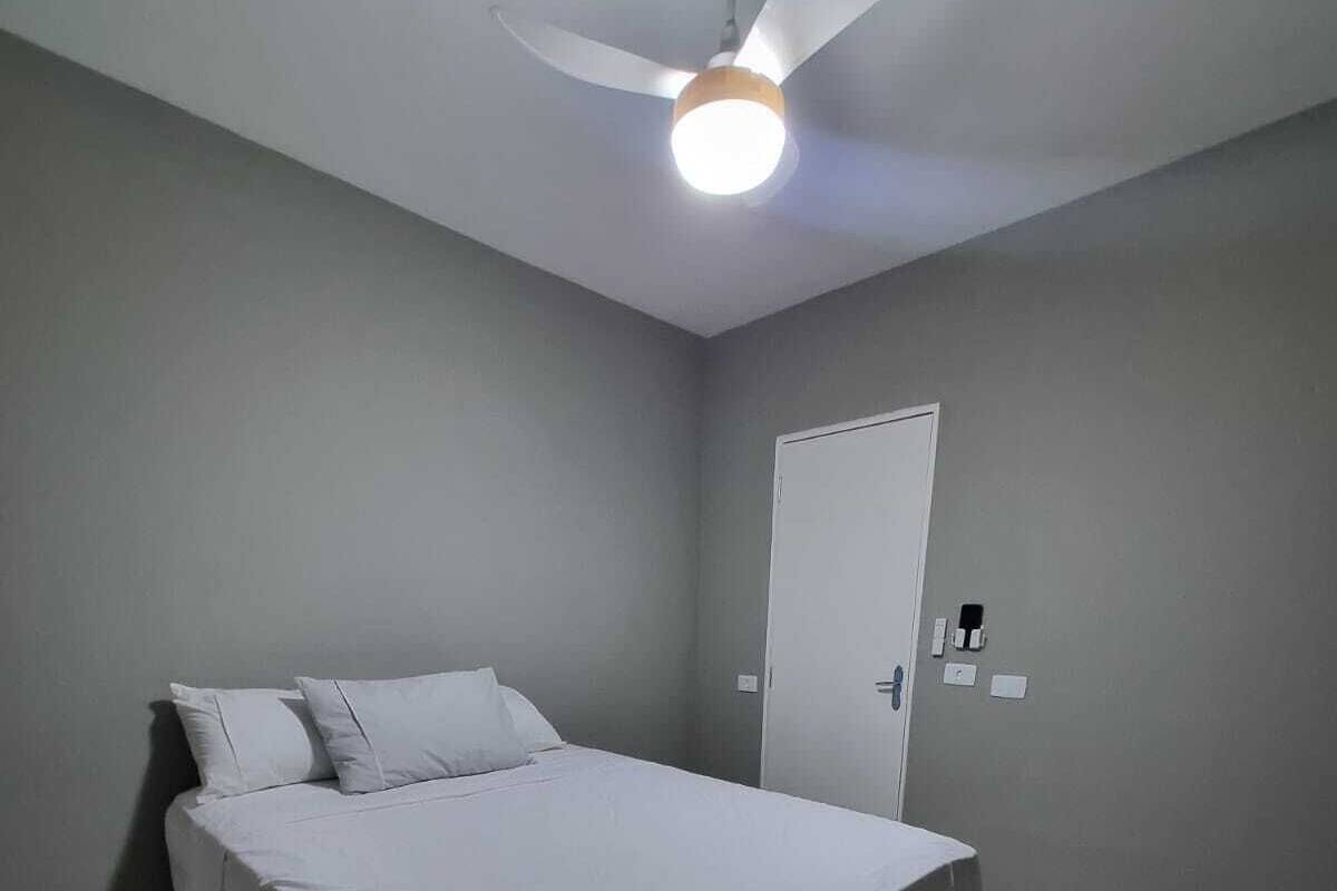 Een slaapkamer met een bed, plafondventilator en een deur.