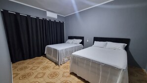 A hotel room with two beds, a ceiling fan, and a patterned floor.