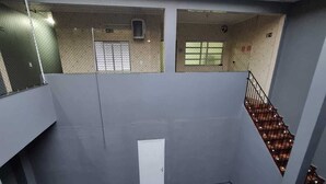 A multi-level building with a grey exterior, a small white door, and a staircase leading to an upper level.