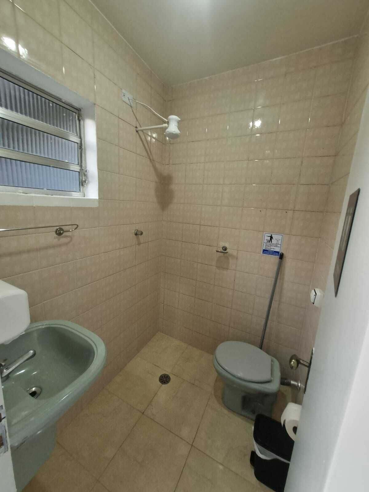 A small, tiled bathroom with a shower, toilet, and sink.
