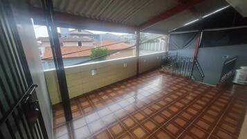 A balcony with tiled flooring, a metal railing, and a view of neighboring buildings.