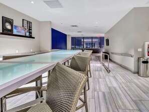 Relax in a stylish space with a pool table, wicker chairs, and city views.