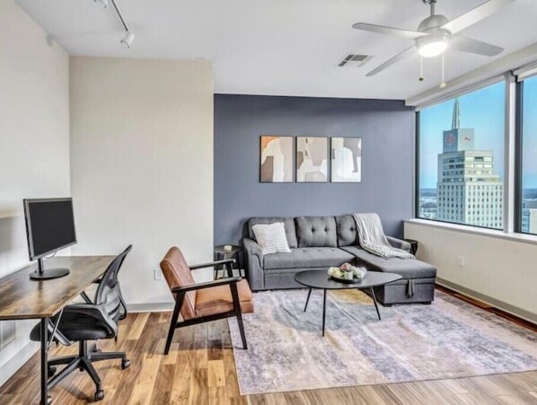 Relax in this stylish living room with a sofa, coffee table, and armchairs, offering a city view.