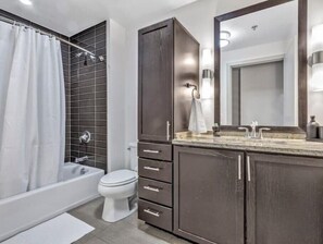 Bathroom features a bathtub, toilet, and vanity with a mirror and sink.