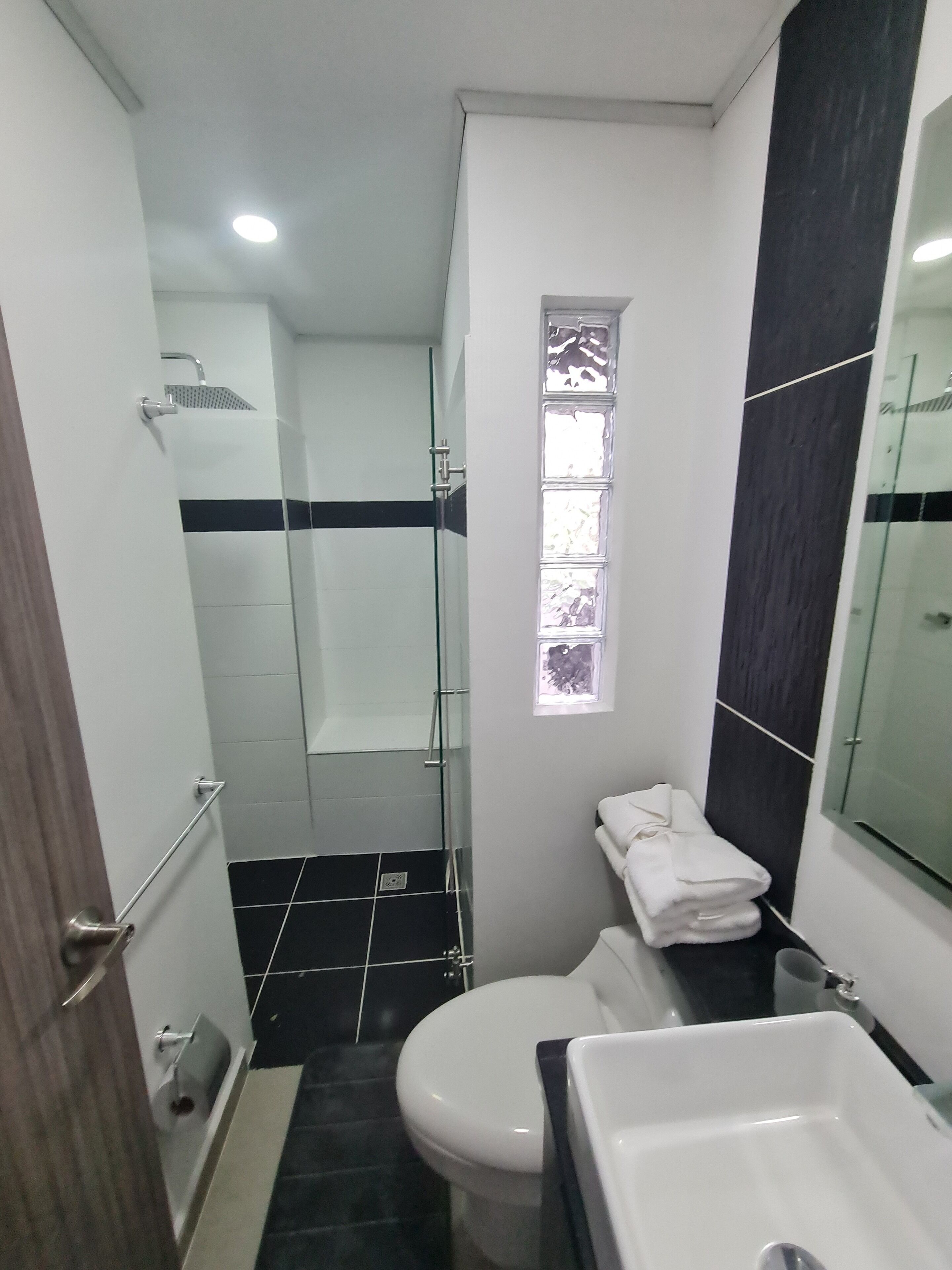 A bathroom with a glass-enclosed shower, a toilet, and a sink.