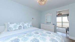 Un dormitorio con cama, cómoda, espejo y vistas al exterior.