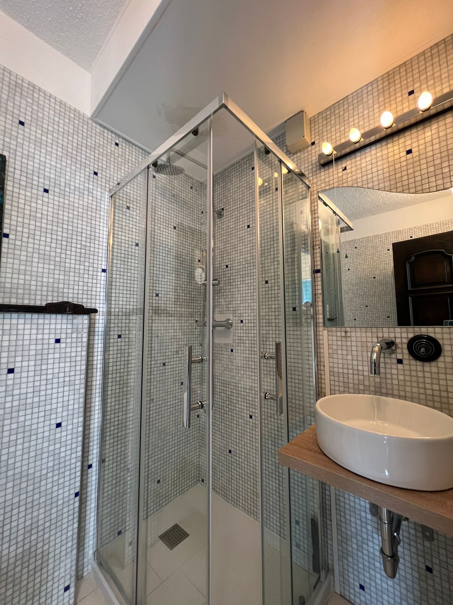 A modern bathroom with a glass-enclosed shower, a white sink, and a tiled backsplash.