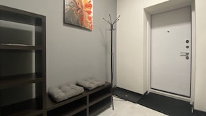 A hallway with a coat rack, a door, and a shelf with cushions. - Apartment  Home Apart Minsk Zaharova 24 (Minsk)
