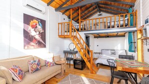 A cozy loft-style bedroom with a wooden staircase, a bed, and a seating area with a couch and chairs. - AYVALIK TRİNGO BUNGALOV (Ayvalik)
