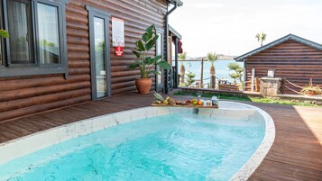 Uma cabana de madeira com piscina, placa de identificação e planta em vaso.