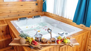 A wooden spa tub with a white interior, surrounded by wooden walls and a window with blue curtains. - AYVALIK TRİNGO BUNGALOV (Ayvalik)