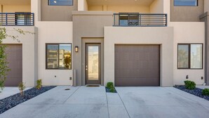 Uma casa moderna de dois andares com garagem, varanda e um pequeno jardim.