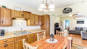 Una cocina con armarios de madera, una mesa de comedor de madera y una araña.