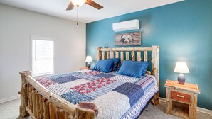 Un dormitorio con cabecera de cama de madera, pared azul y ventilador de techo.