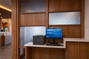 Um balcão de atendimento com monitor de computador, teclado e impressora.