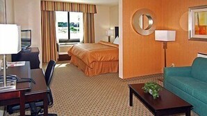 A hotel room with a bed, a desk with a chair, a sofa, a coffee table, a lamp, and a window with curtains. - Fairfield Inn & Suites Hillsboro (Hillsboro)