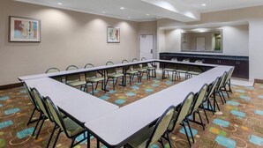 A conference room with a long table and chairs, a kitchen area, and artwork on the walls. - Fairfield Inn & Suites Hillsboro (Hillsboro)